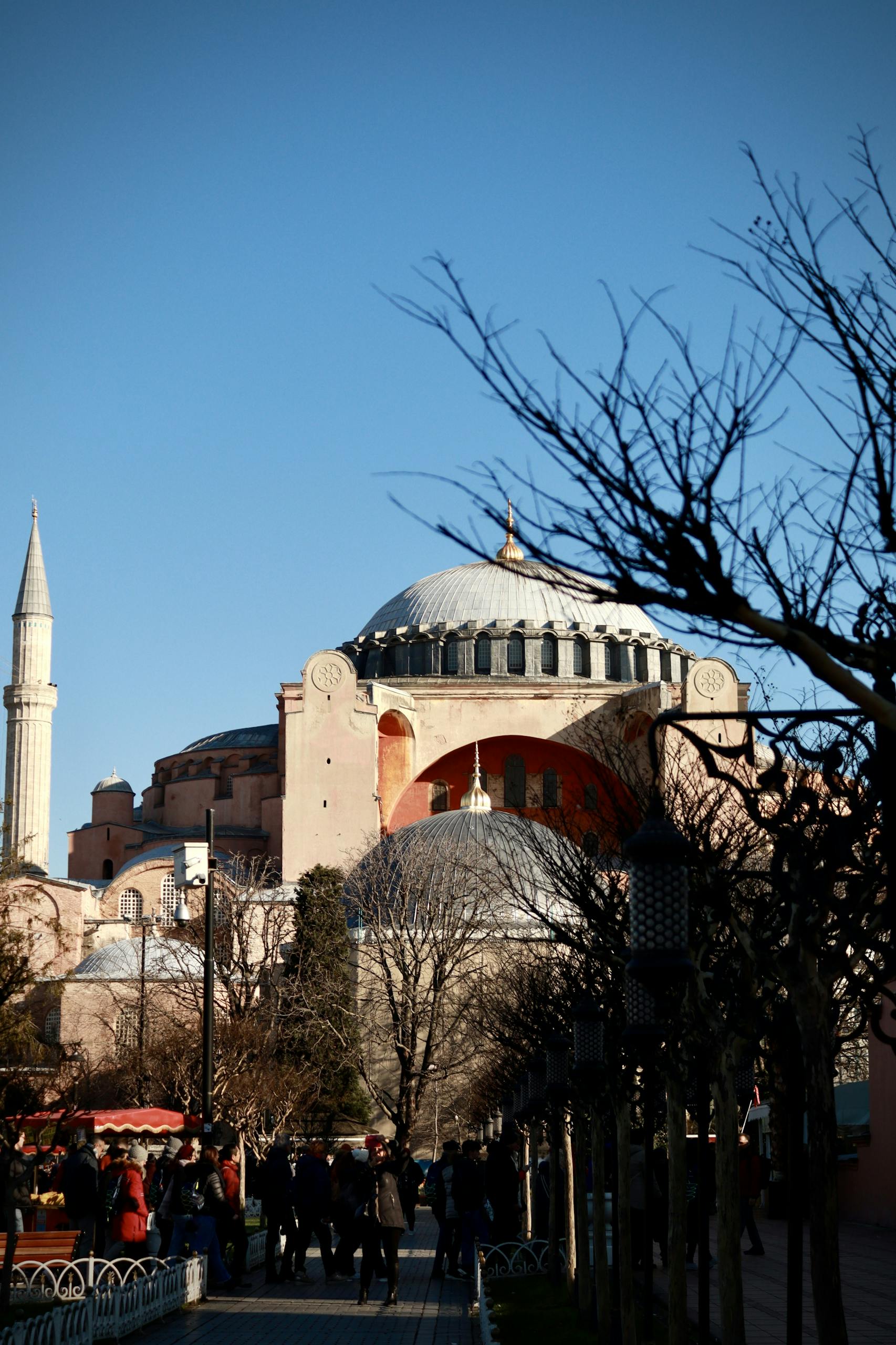 Hagia Sophia in Istanbul beneath a clear sky, surrounded by winter trees and visitors.